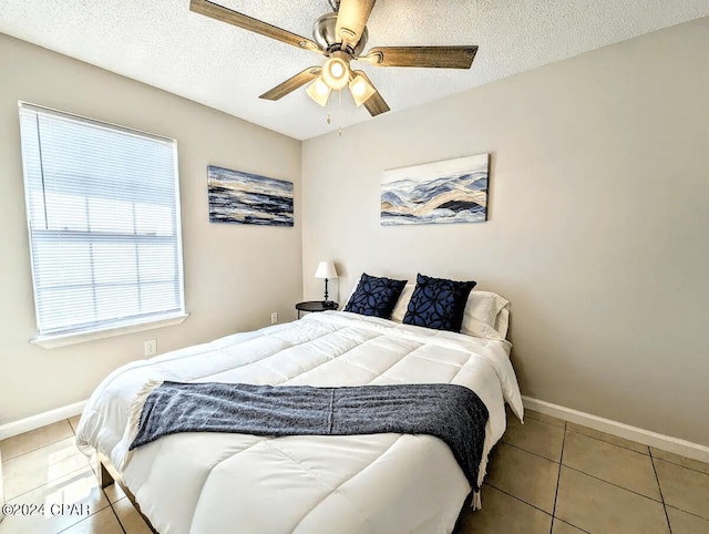 bedroom featuring ceiling fan, light tile patterned flooring, and a textured ceiling