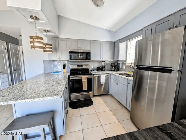 kitchen featuring kitchen peninsula, stainless steel appliances, vaulted ceiling, sink, and hanging light fixtures