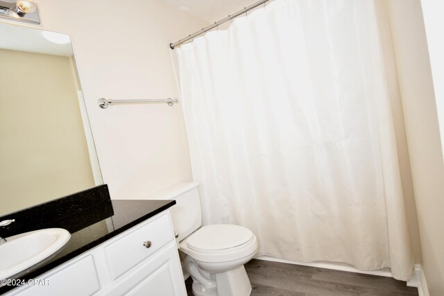 bathroom featuring a shower with shower curtain, vanity, wood-type flooring, and toilet