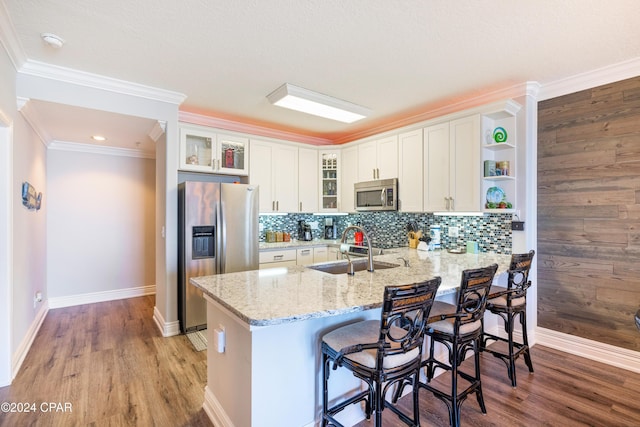 kitchen featuring sink, crown molding, a kitchen bar, white cabinets, and appliances with stainless steel finishes