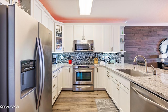 kitchen with light stone countertops, backsplash, stainless steel appliances, sink, and white cabinets