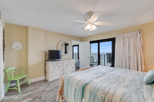 bedroom with access to outside, ceiling fan, light hardwood / wood-style floors, and a textured ceiling