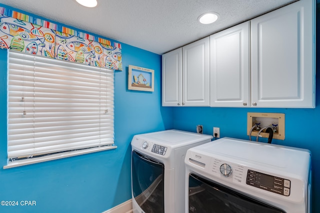 washroom with cabinets, a textured ceiling, and washing machine and dryer