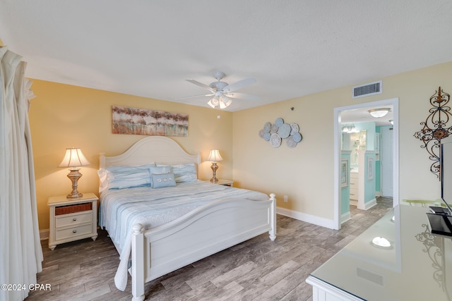 bedroom with hardwood / wood-style floors, ceiling fan, and ensuite bath