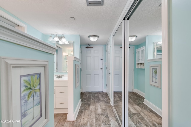 interior space with a textured ceiling, hardwood / wood-style flooring, and sink