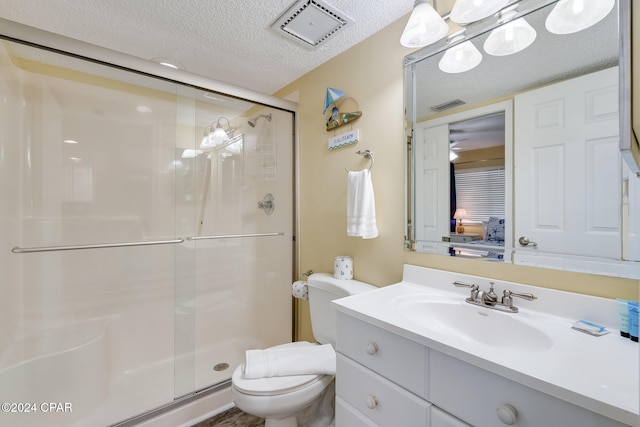 bathroom featuring vanity, a shower with shower door, a textured ceiling, and toilet