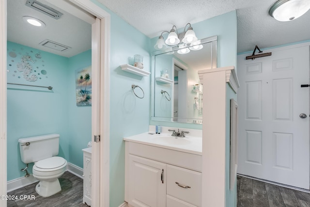 bathroom with toilet, vanity, a textured ceiling, and hardwood / wood-style flooring