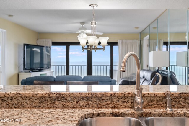 kitchen with a chandelier, light stone counters, and sink