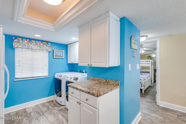 clothes washing area featuring cabinets, a textured ceiling, ceiling fan, light hardwood / wood-style flooring, and independent washer and dryer