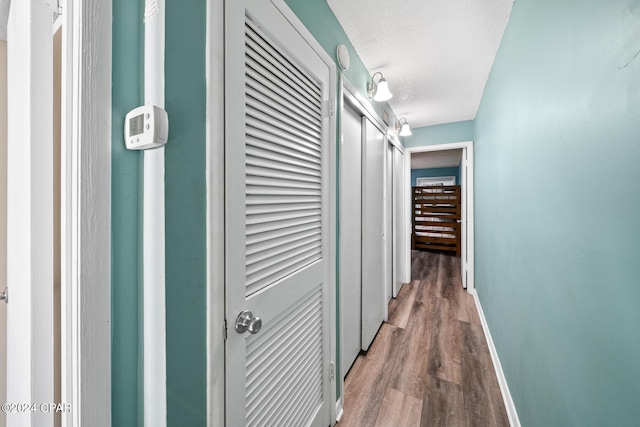 hallway with hardwood / wood-style floors and a textured ceiling