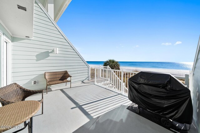 balcony with a water view, grilling area, and a beach view