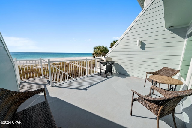 balcony featuring a view of the beach, area for grilling, and a water view