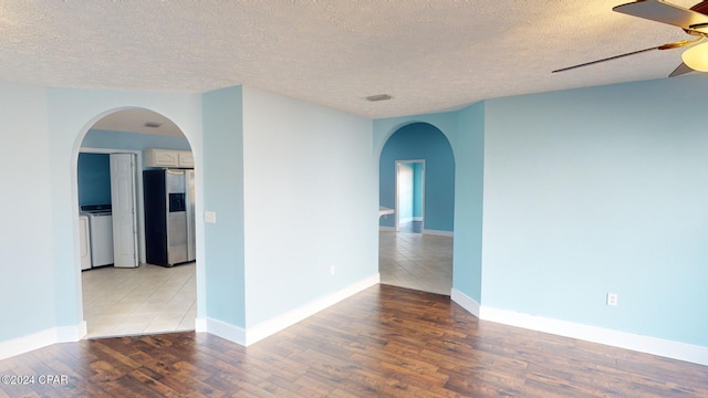 spare room featuring ceiling fan, washing machine and dryer, a textured ceiling, and light hardwood / wood-style flooring