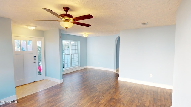 foyer entrance with ceiling fan, a textured ceiling, and light wood-type flooring