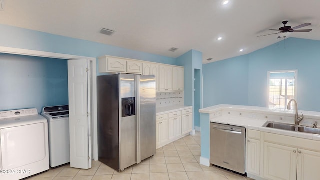 kitchen with ceiling fan, sink, stainless steel appliances, separate washer and dryer, and vaulted ceiling