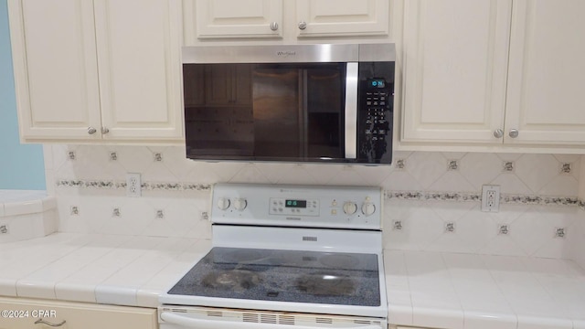 kitchen featuring white cabinetry, electric stove, and tasteful backsplash