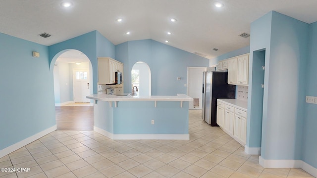 kitchen featuring kitchen peninsula, tasteful backsplash, stainless steel appliances, a breakfast bar area, and lofted ceiling