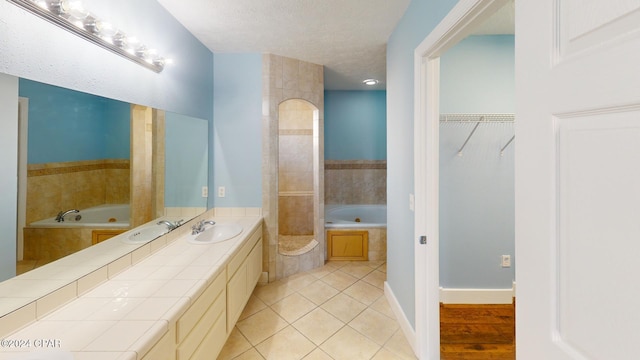 bathroom with tile patterned floors, separate shower and tub, vanity, and a textured ceiling