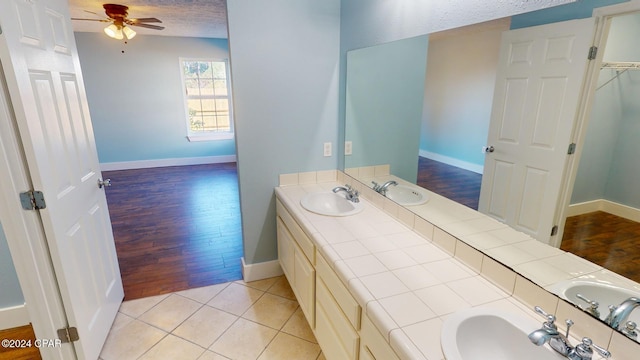 bathroom with hardwood / wood-style flooring, vanity, ceiling fan, and a textured ceiling