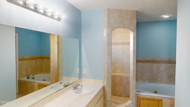 bathroom featuring tiled bath, vanity, and a textured ceiling