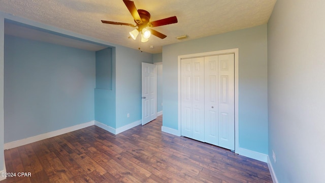 unfurnished bedroom featuring a textured ceiling, a closet, ceiling fan, and dark hardwood / wood-style floors