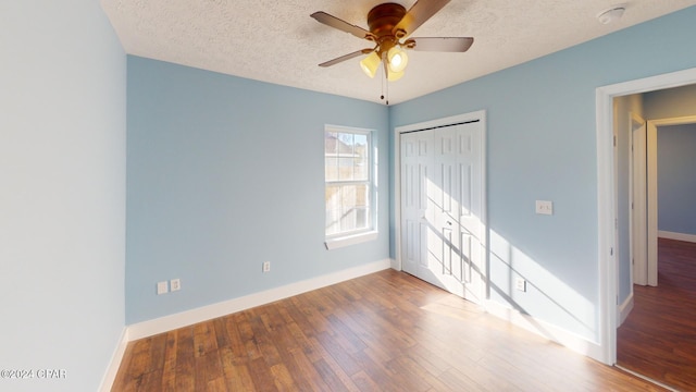 unfurnished bedroom featuring wood-type flooring, a textured ceiling, a closet, and ceiling fan