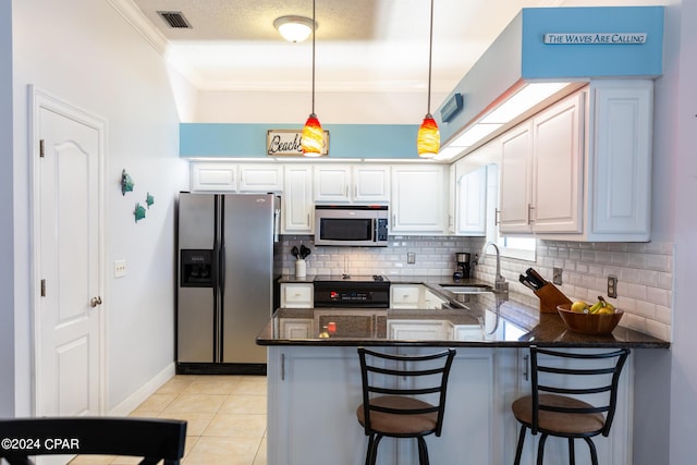 kitchen featuring kitchen peninsula, appliances with stainless steel finishes, decorative light fixtures, white cabinetry, and a breakfast bar area