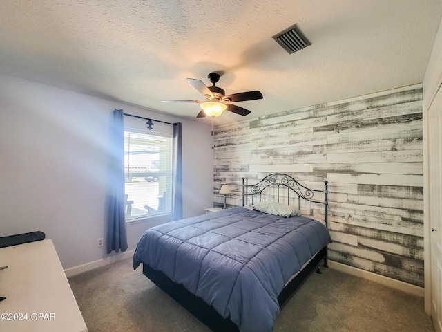 carpeted bedroom featuring a textured ceiling, ceiling fan, and wood walls