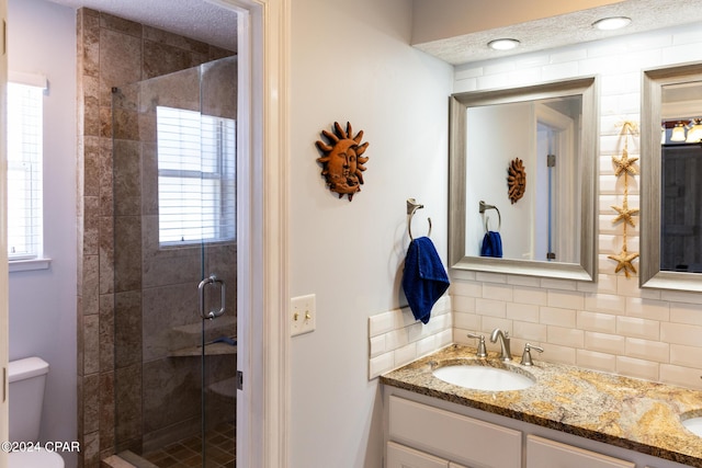 bathroom with decorative backsplash, vanity, an enclosed shower, and toilet