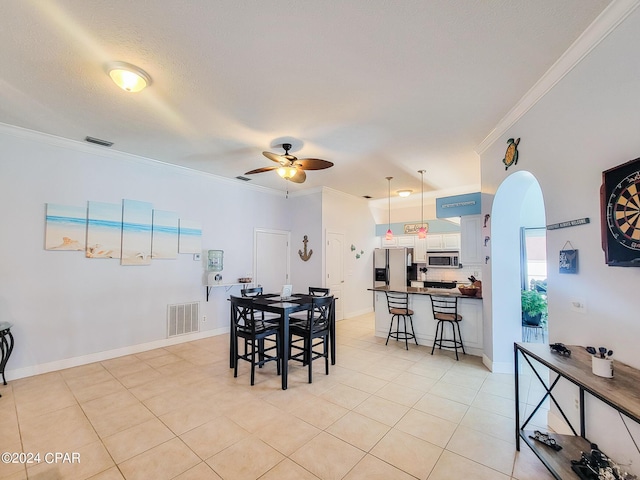 tiled dining area featuring ceiling fan, crown molding, and a textured ceiling