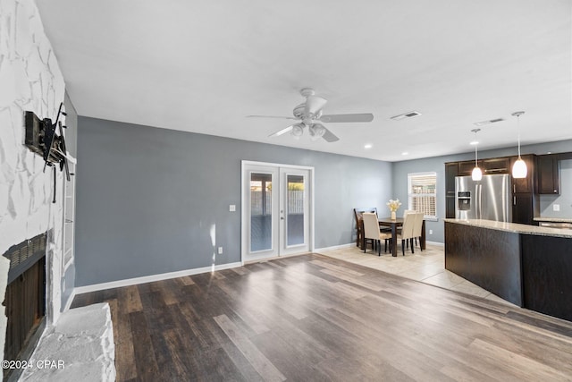 unfurnished living room featuring ceiling fan, light hardwood / wood-style flooring, french doors, and a fireplace