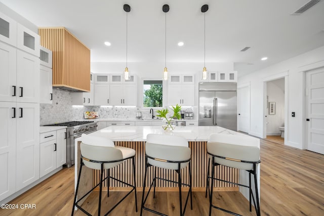 kitchen featuring white cabinetry, high quality appliances, a center island, and light hardwood / wood-style floors