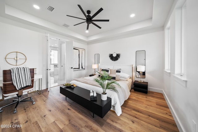 bedroom featuring a tray ceiling, ceiling fan, and wood-type flooring