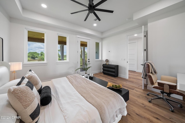 bedroom featuring light wood-type flooring, a raised ceiling, and ceiling fan