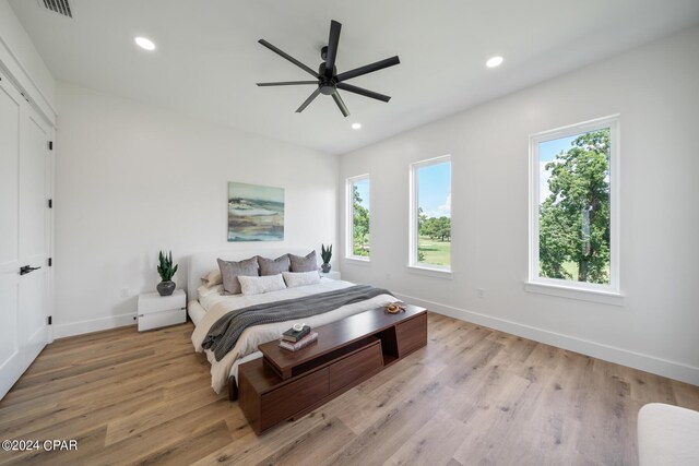 bedroom featuring ceiling fan, multiple windows, and light hardwood / wood-style flooring