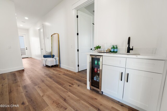 corridor featuring light hardwood / wood-style flooring, beverage cooler, and sink