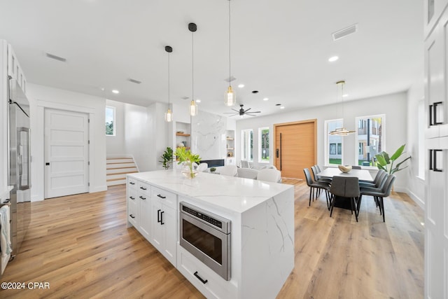 kitchen with a center island, decorative light fixtures, white cabinetry, and light hardwood / wood-style floors