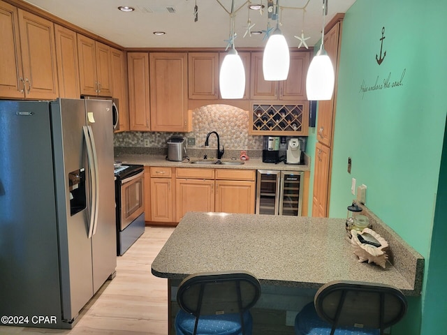 kitchen with sink, beverage cooler, stainless steel appliances, decorative light fixtures, and a breakfast bar