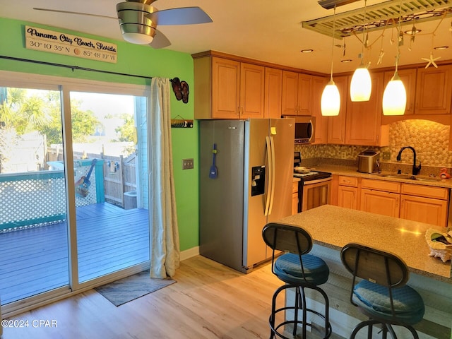 kitchen with a kitchen bar, tasteful backsplash, stainless steel appliances, sink, and decorative light fixtures