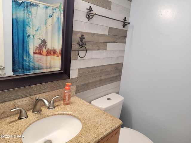 bathroom with vanity, toilet, and wooden walls