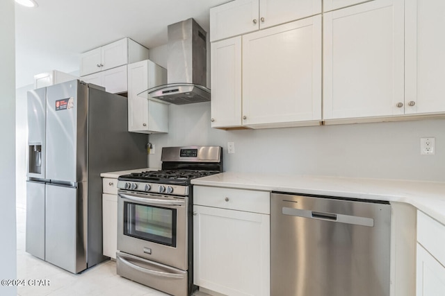 kitchen with white cabinets, appliances with stainless steel finishes, and wall chimney range hood