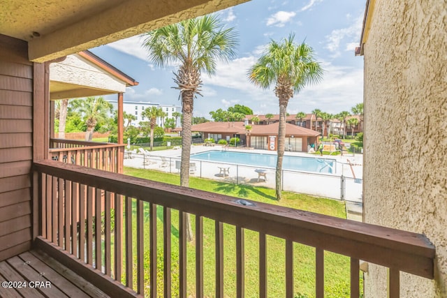 wooden terrace with a community pool and a yard