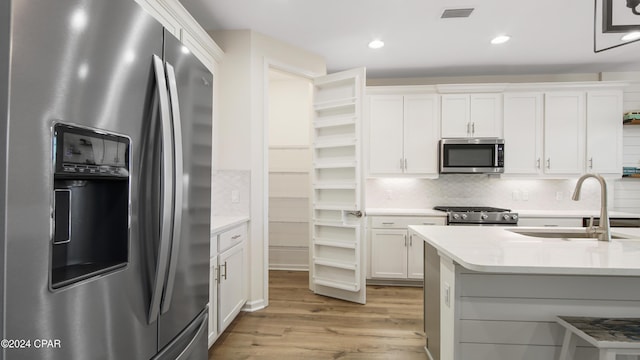 kitchen featuring sink, white cabinetry, backsplash, stainless steel appliances, and light hardwood / wood-style floors