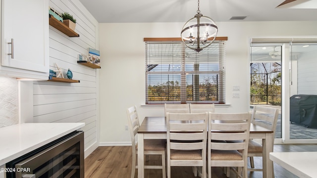 dining area featuring wine cooler, dark hardwood / wood-style floors, a chandelier, and wood walls