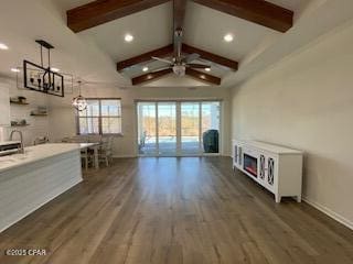 unfurnished living room with dark wood-type flooring, ceiling fan, and vaulted ceiling with beams