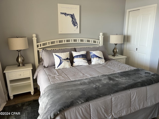 bedroom with dark hardwood / wood-style floors and a closet