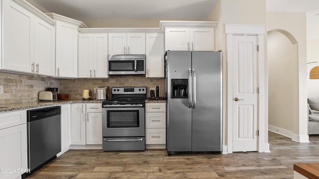 kitchen with white cabinets, dark hardwood / wood-style floors, light stone countertops, and appliances with stainless steel finishes