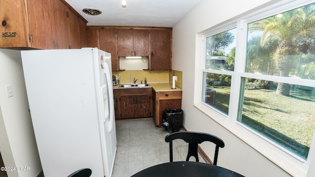 kitchen with a wealth of natural light, sink, and white refrigerator with ice dispenser