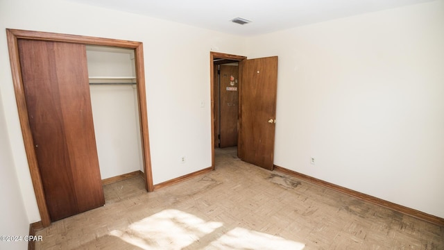 unfurnished bedroom featuring light parquet floors and a closet