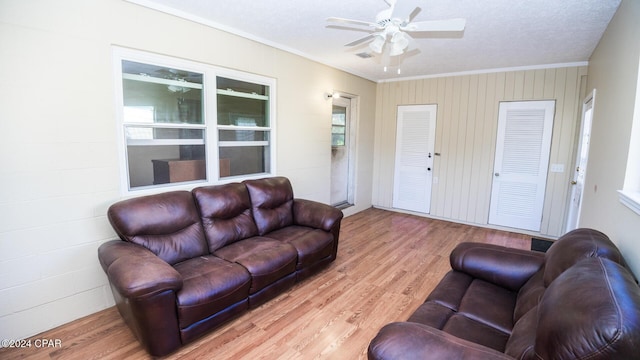 living room with ornamental molding, a textured ceiling, ceiling fan, hardwood / wood-style floors, and wood walls